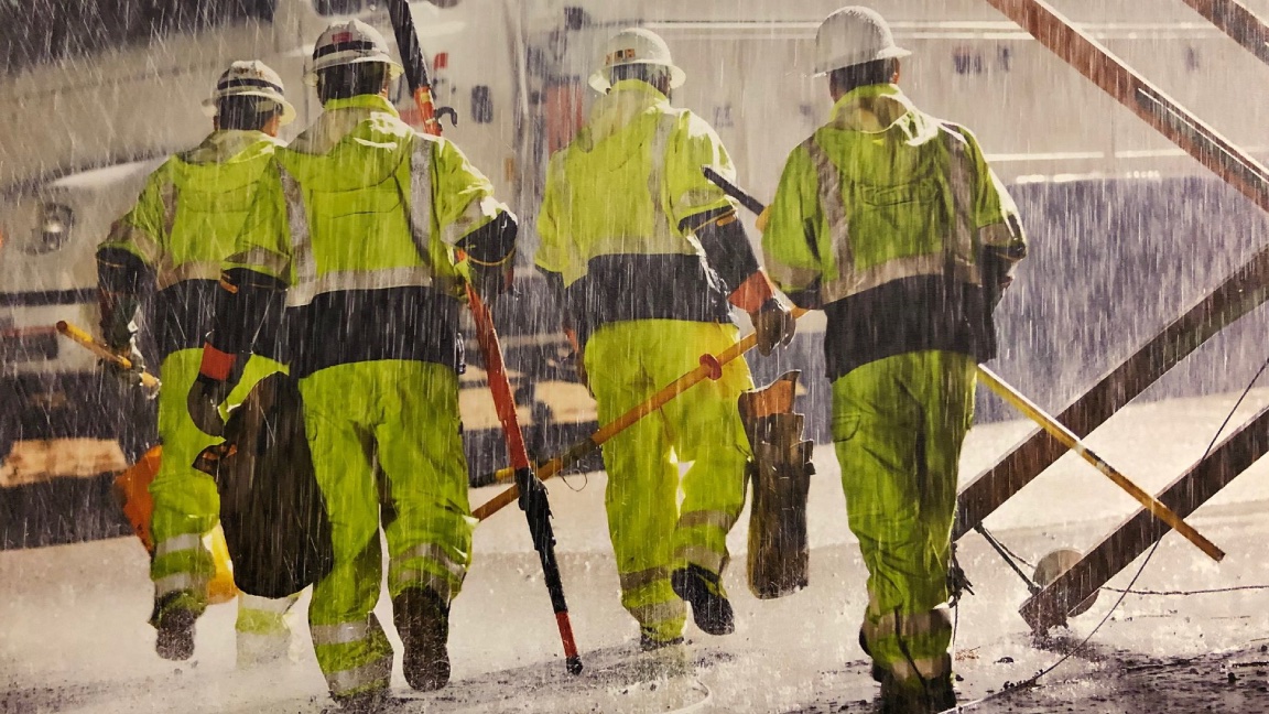 Image of workers in PPE clothing walking in the rain